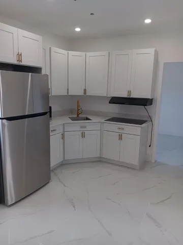 a kitchen with a sink a refrigerator and white cabinets