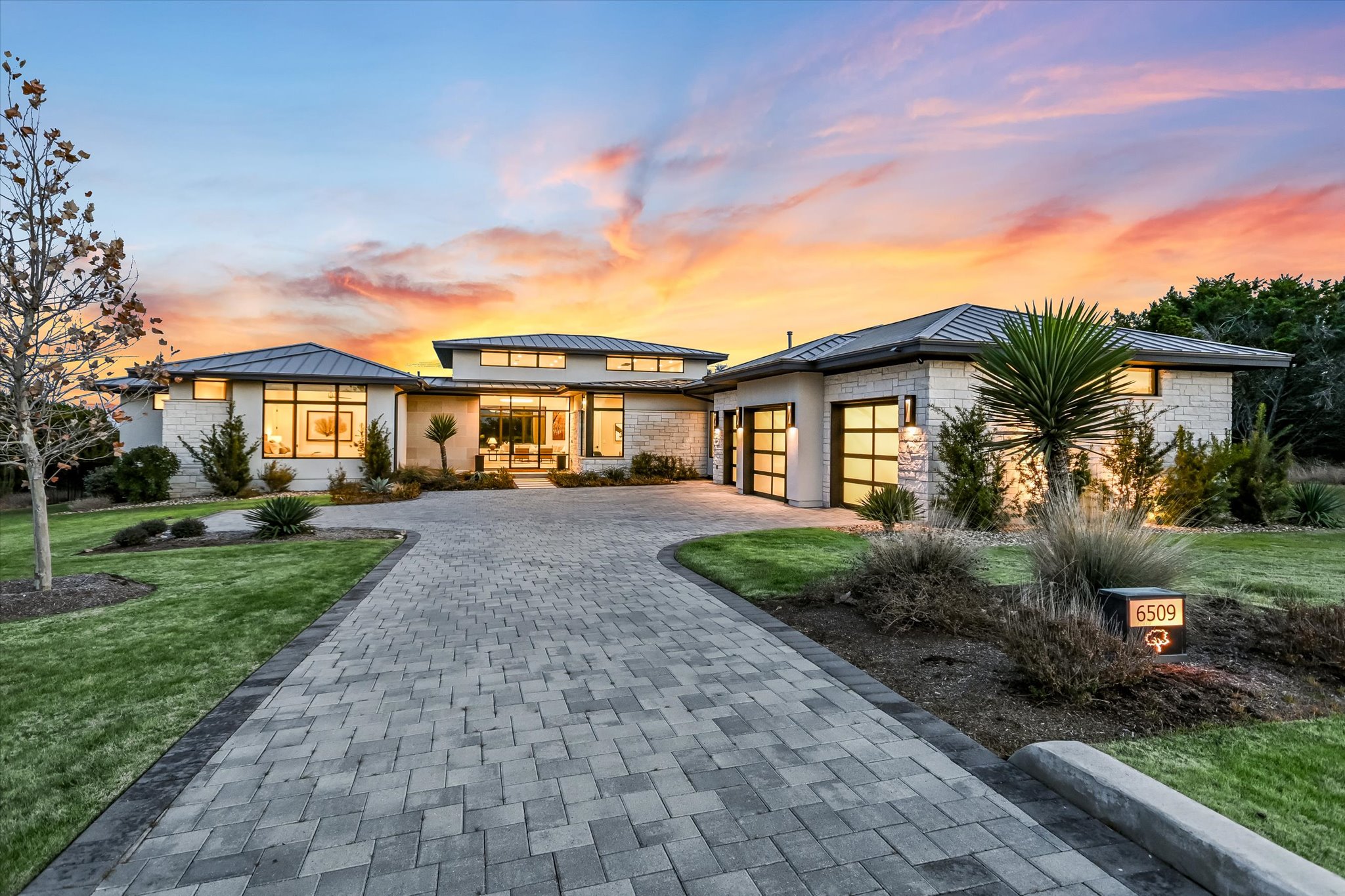 6509 Madrone Tree Lane Austin, TX 78738 - Photo 2 of 40 Prairie-style home featuring a standing seam roof, decorative driveway, a front lawn, roof mounted solar panels, and a garage