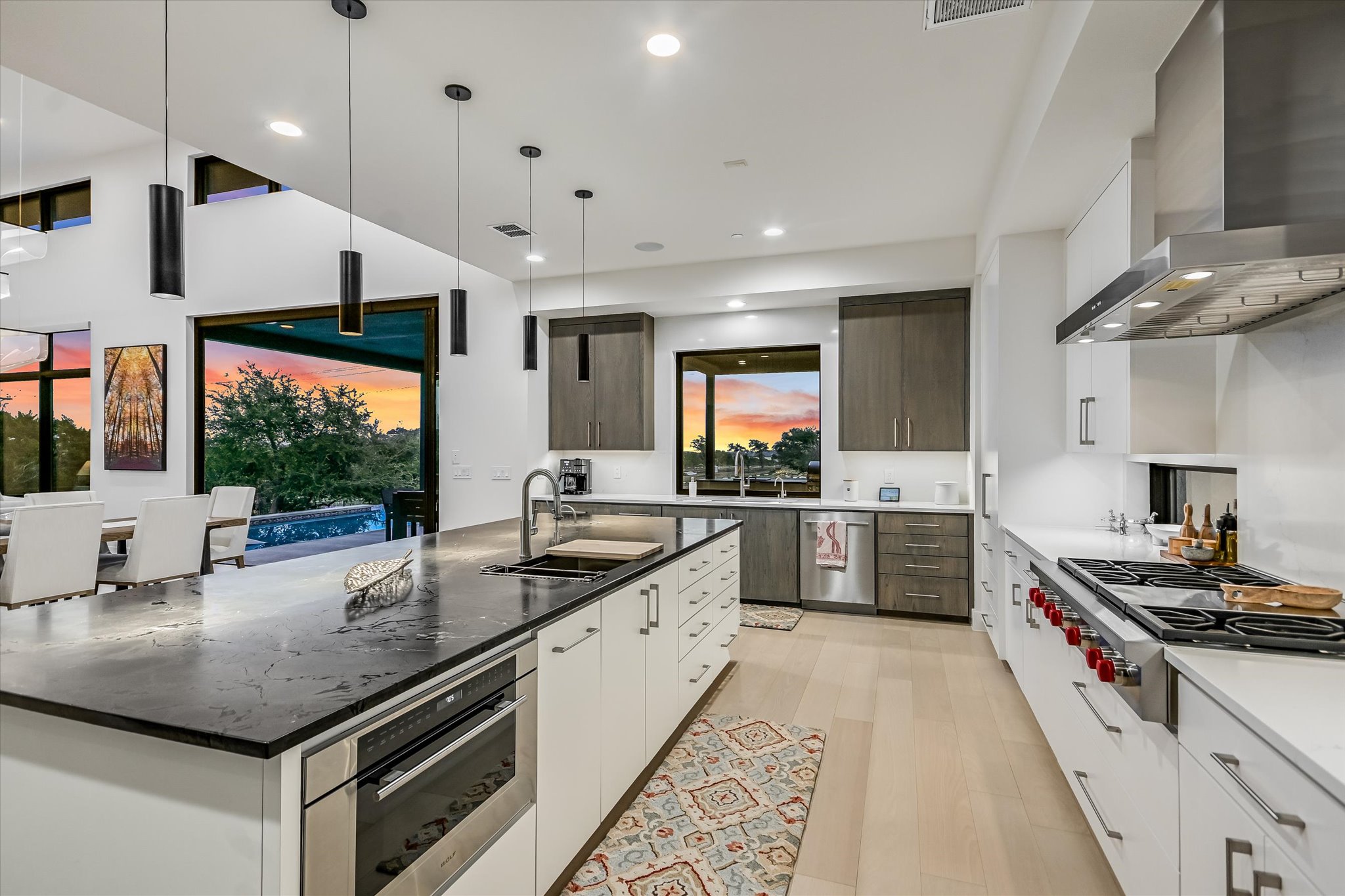 6509 Madrone Tree Lane Austin, TX 78738 - Photo 10 of 40 Two tone kitchen featuring two tone cabinetry, decorative light fixtures, modern cabinets, an island with sink, and stainless steel appliances