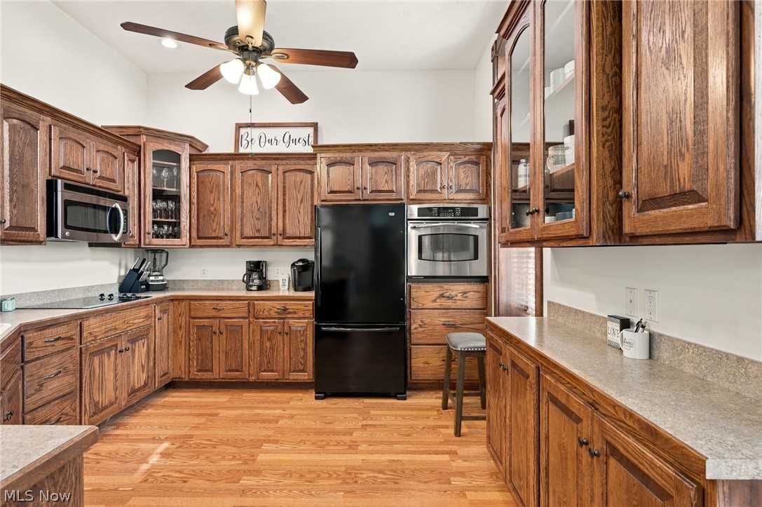 42764 Russia Road Elyria, OH 44035 - Photo 18 of 50 Expansive kitchen featuring wood-finish flooring, abundant wood cabinetry, integrated stainless steel appliances, and a ceiling fan with integrated lighting