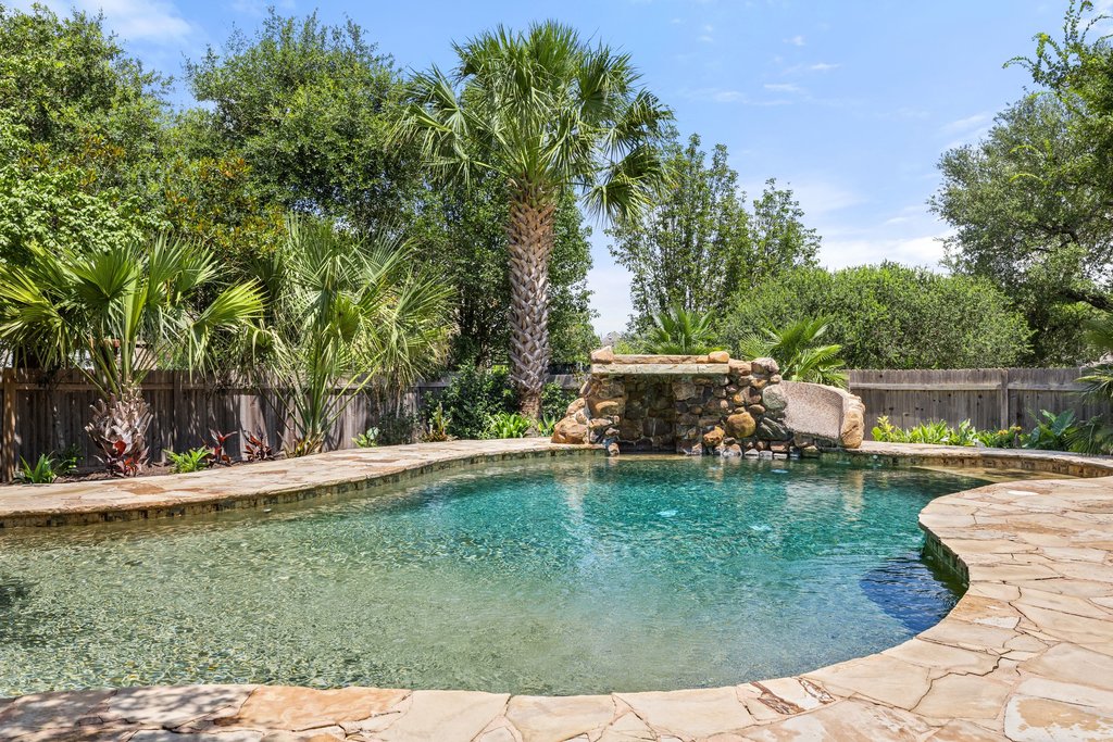 6704 Kiev Cove Austin, TX 78739 - Photo 36 of 37 A tranquil backyard oasis features a freeform swimming pool with natural stone coping and a rock waterfall feature.