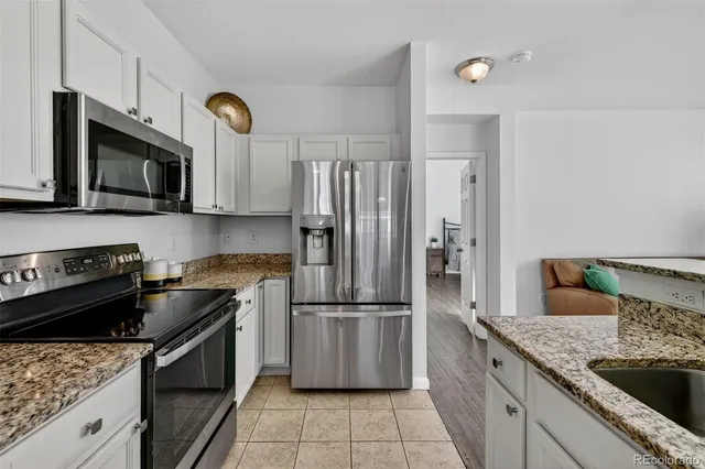 a kitchen with granite countertop a refrigerator stove and microwave