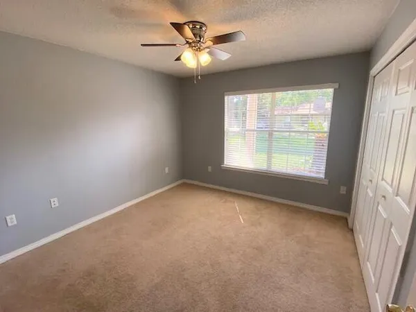 an empty room with a window and a ceiling fan