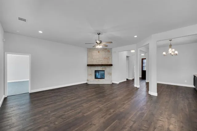 a view of an empty room with wooden floor and a kitchen