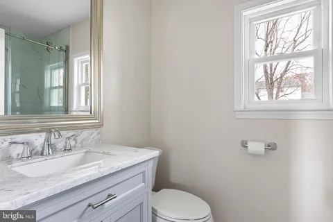 a bathroom with a granite countertop toilet sink and mirror