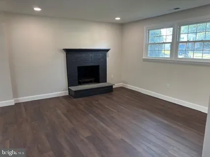 an empty room with wooden floor and fireplace