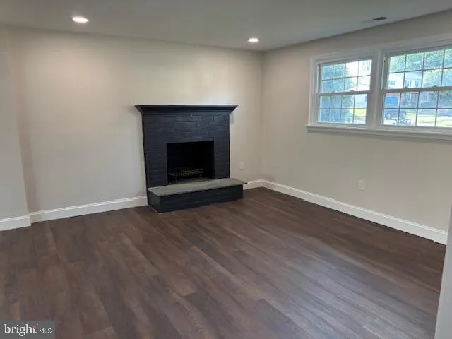 an empty room with wooden floor and fireplace