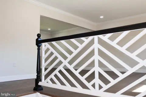 a view of an empty room with wooden floor and white walls