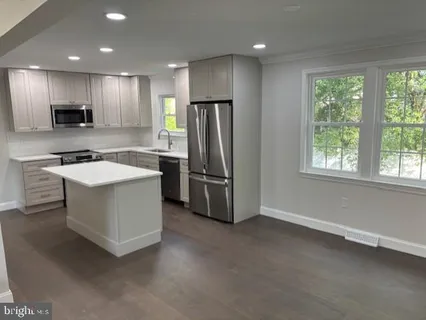 a kitchen with stainless steel appliances granite countertop a refrigerator a sink a stove and a refrigerator with wooden floor