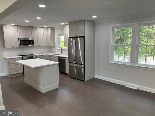 a kitchen with stainless steel appliances granite countertop a refrigerator a sink a stove and a refrigerator with wooden floor