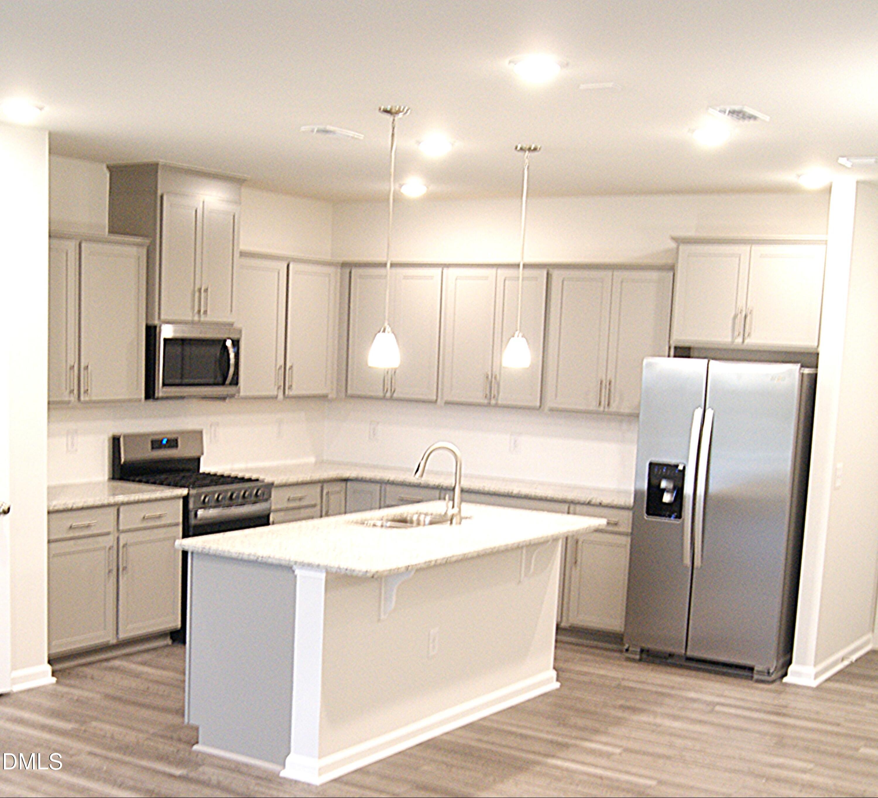 295 Glenmore Gardens Road Raleigh, NC 27603 - Photo 5 of 30 a kitchen with a refrigerator a sink and cabinets