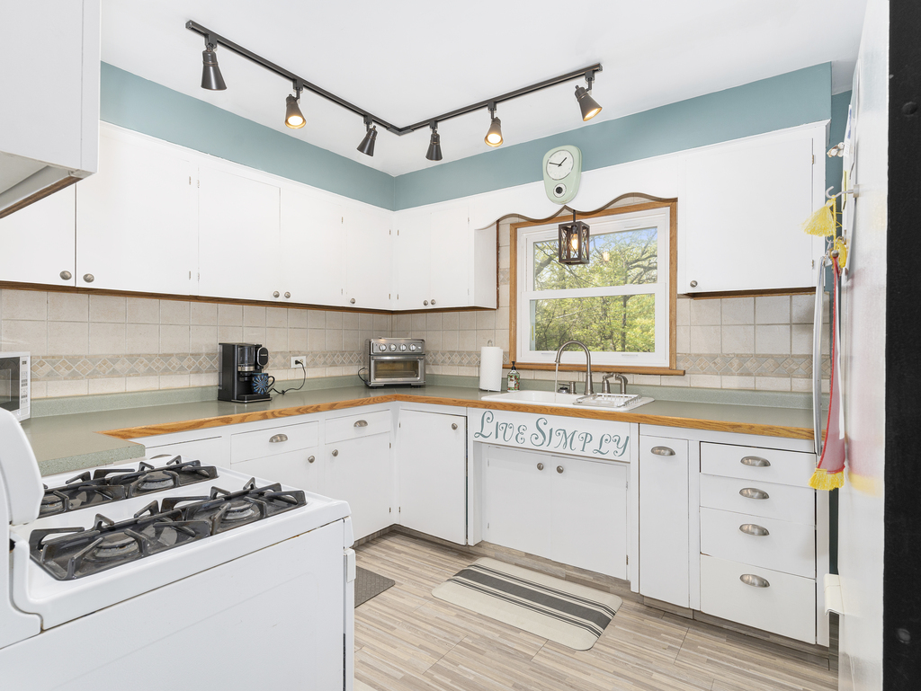 1604 Pine Road Homewood, IL 60430 - Photo 6 of 17 a kitchen with stainless steel appliances a sink a stove and white cabinets next to a window