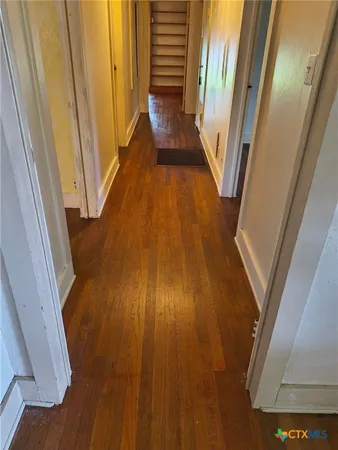 a view of a hallway with wooden floor and staircase
