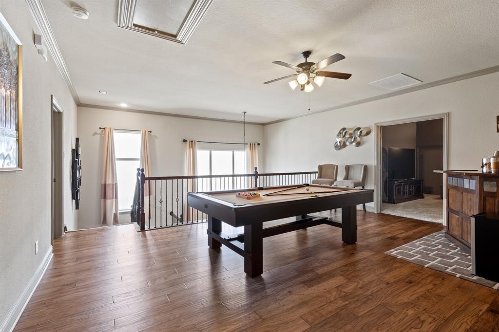 a room with wooden floor pool table and windows