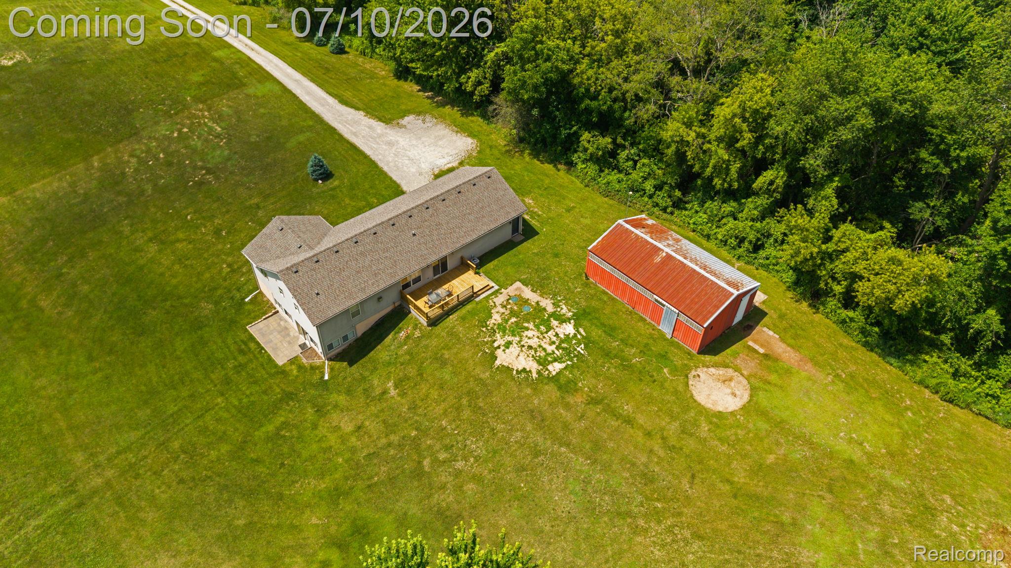 3144 North Nicholson Road Fowlerville, MI 48836 - Photo 6 of 70 Expansive property featuring a residence with a multi-level deck, a detached red barn with a metal roof, and a gravel driveway