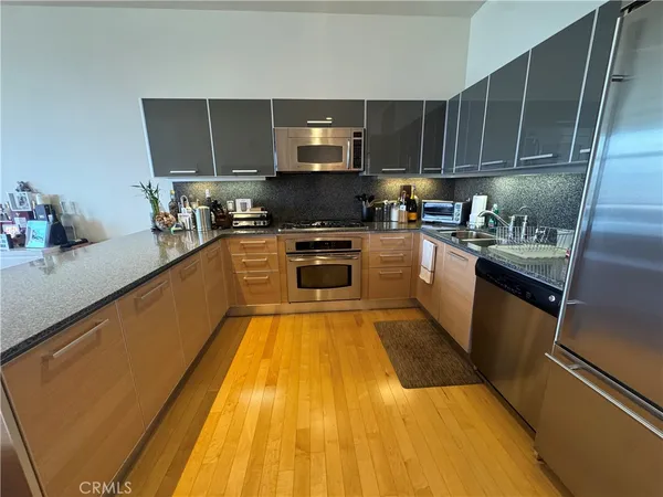 a kitchen with stainless steel appliances granite countertop wooden cabinets a stove top oven a sink and dishwasher