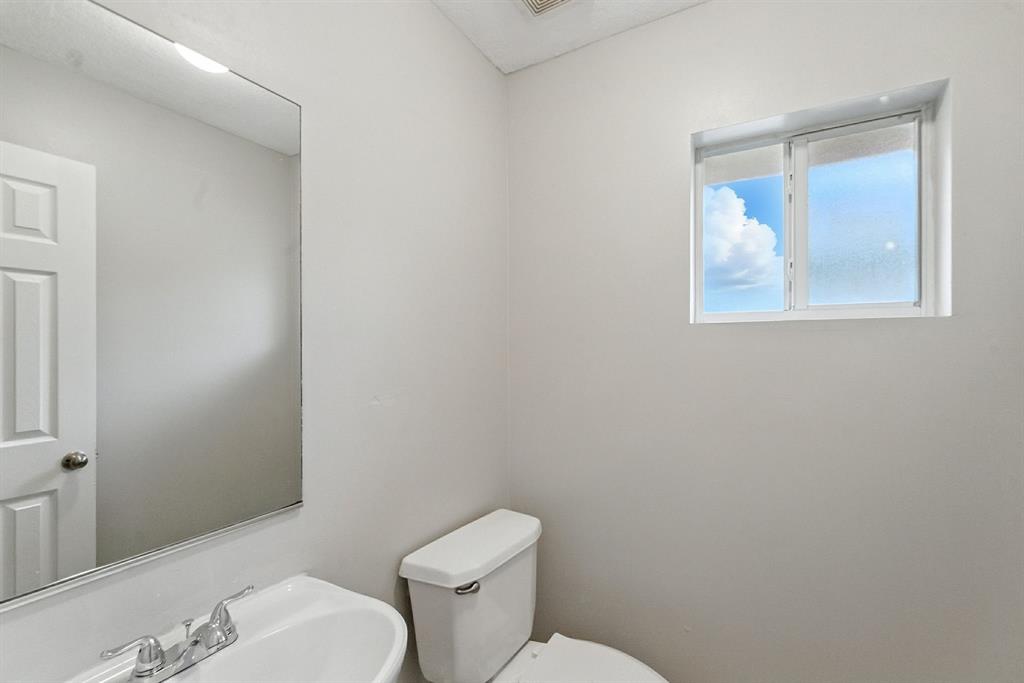 25355 Southwest 135th Court Homestead, FL 33032 - Photo 29 of 40 a white toilet sitting next to a bathroom sink and vanity
