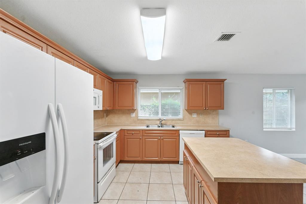 25355 Southwest 135th Court Homestead, FL 33032 - Photo 9 of 40 a kitchen with a sink a refrigerator a window and cabinets