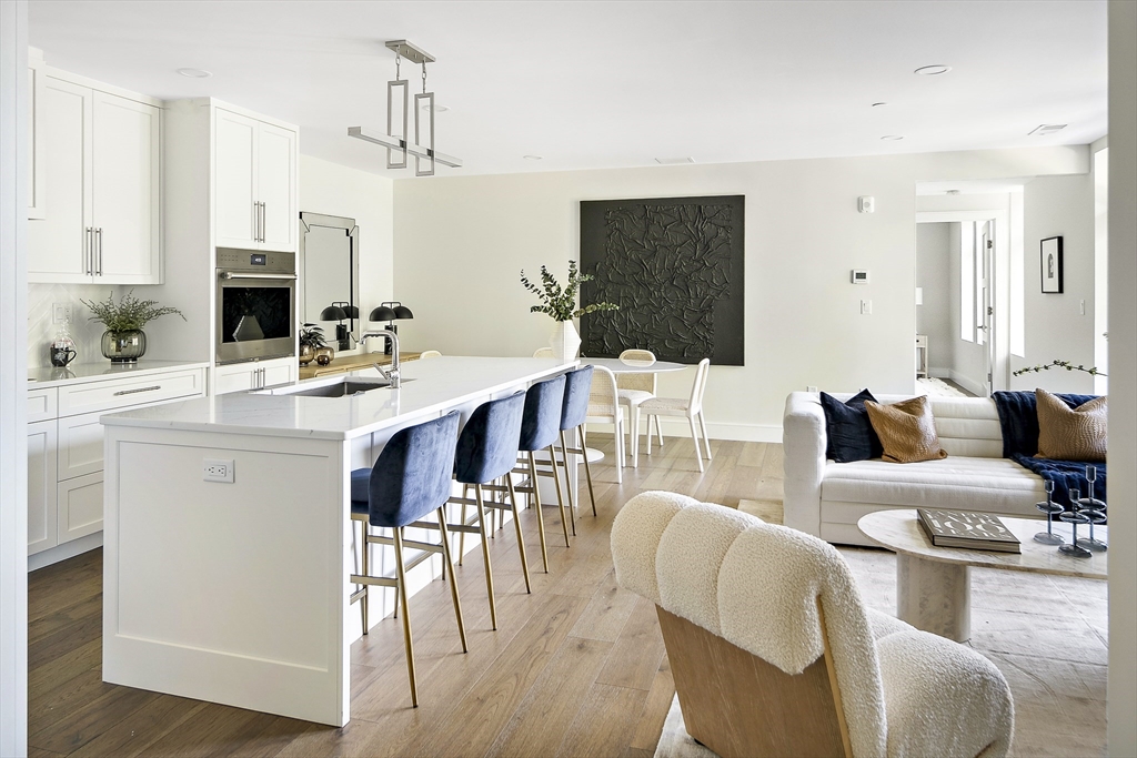 20 Kinmonth Road, Unit 301 Newton, MA 02468 - Photo 11 of 30 a living room with furniture a wooden floor and a kitchen view