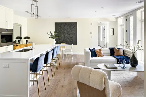 a living room with furniture a flat screen tv and kitchen view