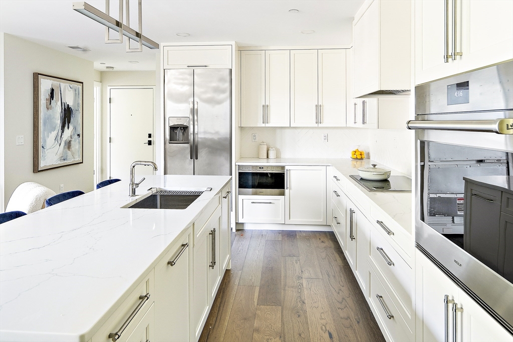20 Kinmonth Road, Unit 301 Newton, MA 02468 - Photo 3 of 30 a large white kitchen with stainless steel appliances granite countertop a lot of counter space and wooden floors