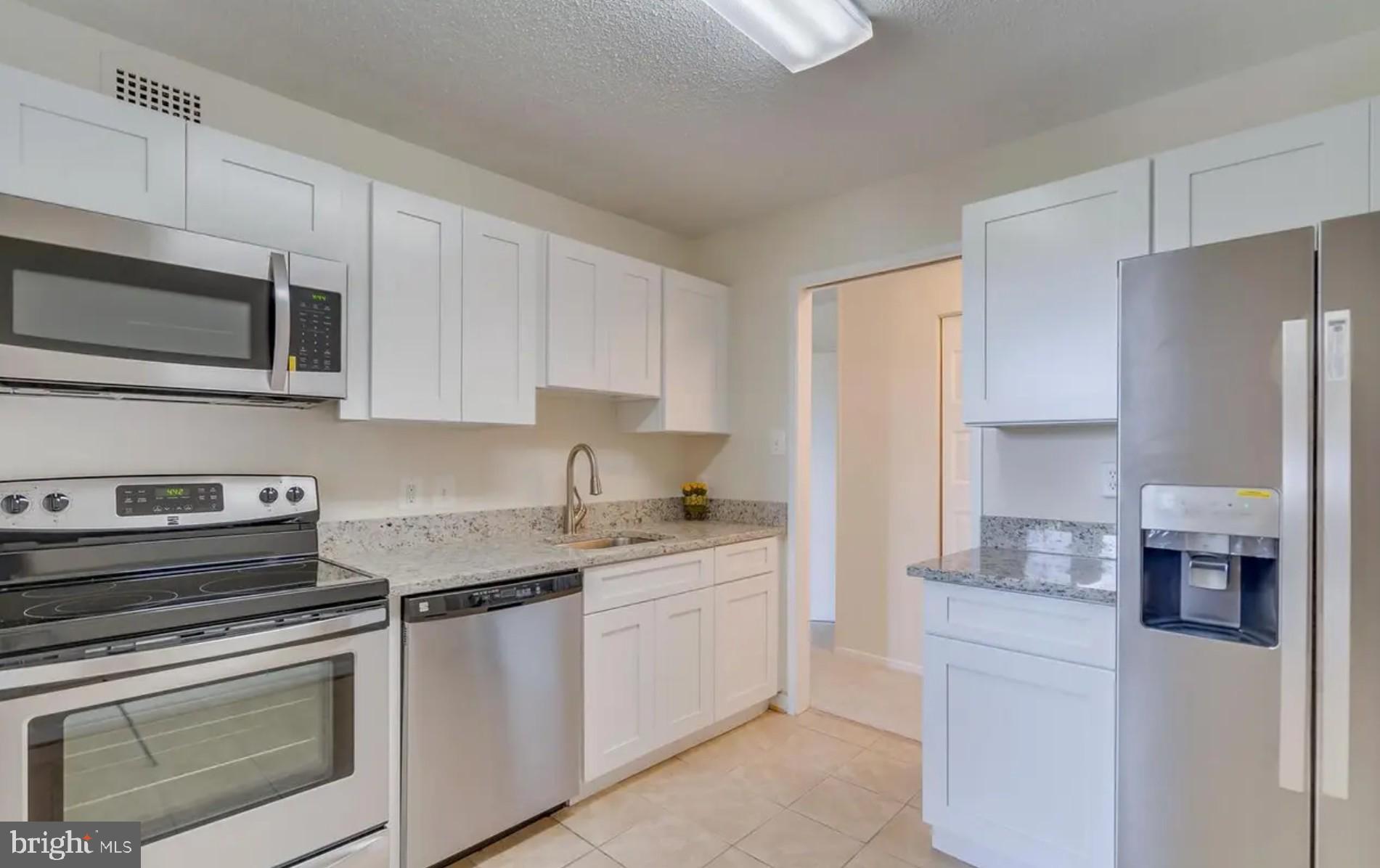 2311 Pimmit Drive, Unit 808 Falls Church, VA 22043 - Photo 8 of 24 a kitchen with stainless steel appliances granite countertop white cabinets a sink a stove a refrigerator and a microwave