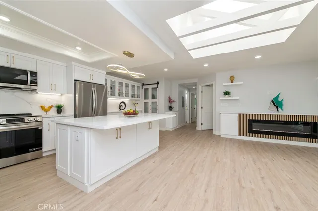 a kitchen with stainless steel appliances a stove a sink cabinets and a wooden floor