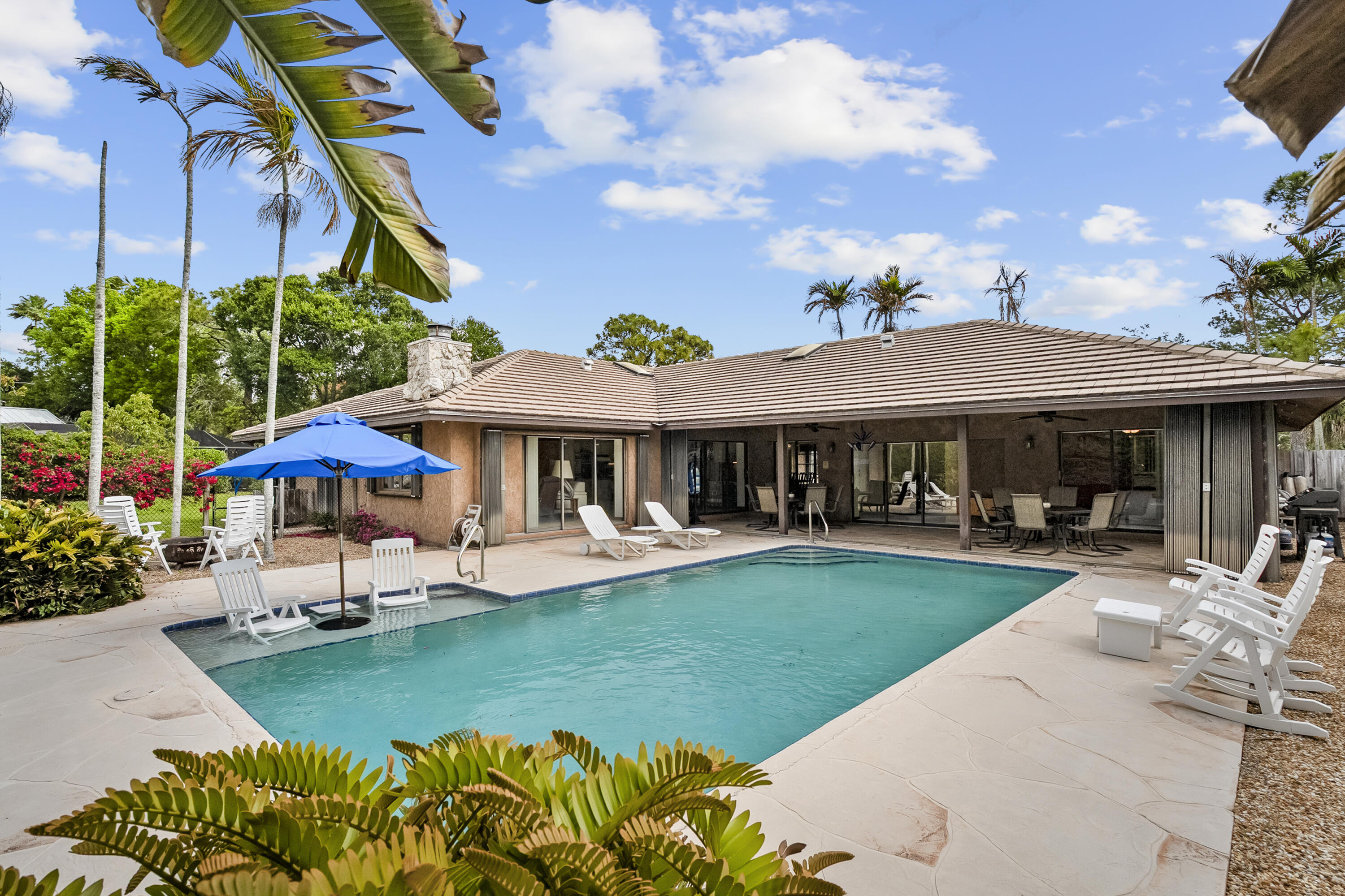 18815 South Golden Hawk Trail Jupiter, FL 33458 - Photo 4 of 49 a patio with a table and chairs under an umbrella