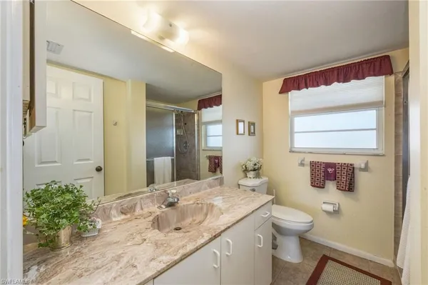 a bathroom with a granite countertop sink mirror vanity and toilet