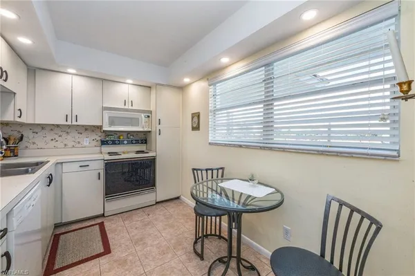 a kitchen with stainless steel appliances granite countertop a stove a sink a refrigerator and a dining table with wooden floor