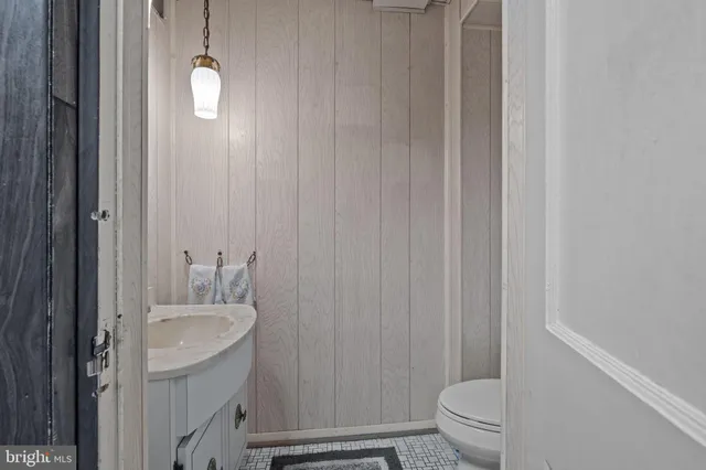 a bathroom with a granite countertop sink vanity mirror and toilet