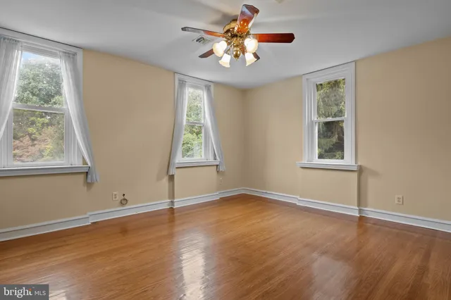 a view of an empty room with window and wooden floor