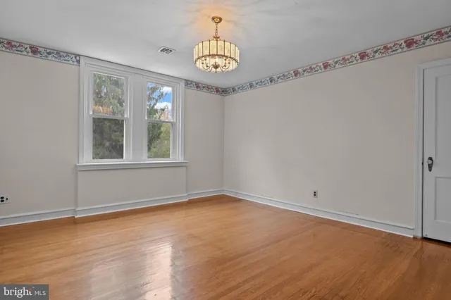 a view of an empty room with window and wooden floor
