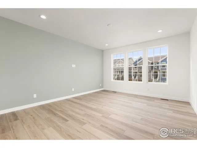 a view of an empty room with wooden floor and windows