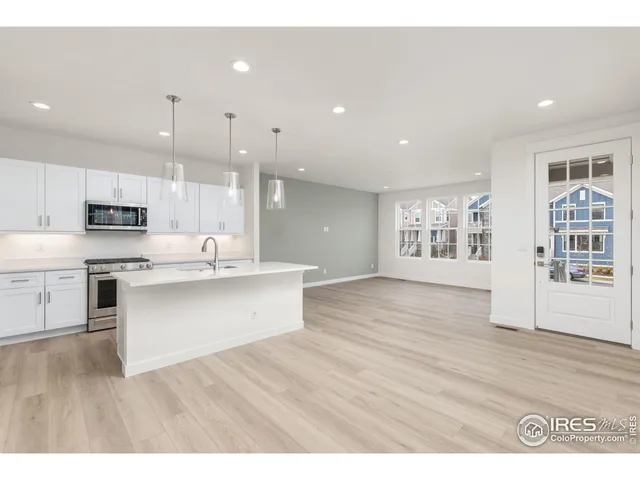 a open kitchen with stainless steel appliances granite countertop a refrigerator a sink dishwasher and a wooden cabinets with wooden floor