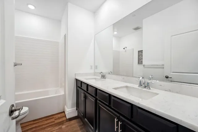 a bathroom with a granite countertop sink a toilet a shower and a mirror