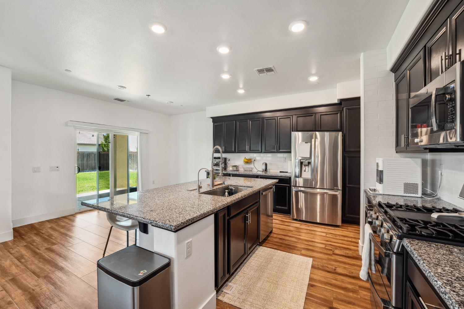 2074 Abbeylane Way Olivehurst, CA 95961 - Photo 7 of 39 a kitchen with stainless steel appliances granite countertop a stove top oven a sink dishwasher and a refrigerator with wooden floor