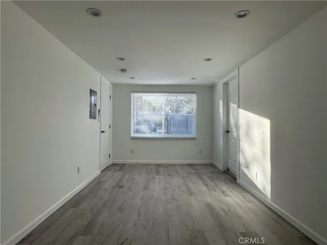 a view of an empty room with a window and wooden floor