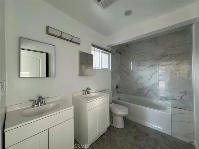a bathroom with a toilet a sink a mirror a bathtub and vanity