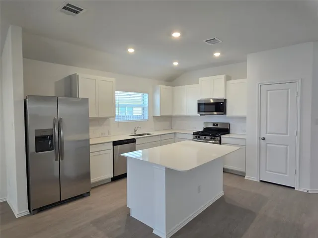 a large kitchen with kitchen island a sink stainless steel appliances and cabinets