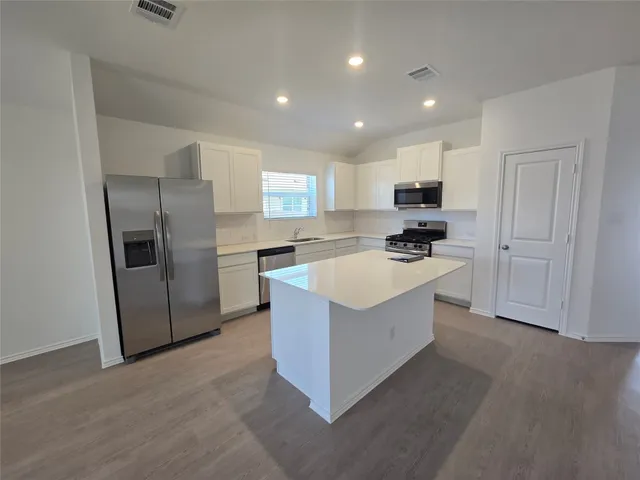 a kitchen with stainless steel appliances a refrigerator a sink a stove a microwave and island