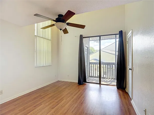a view of empty room with wooden floor and fan
