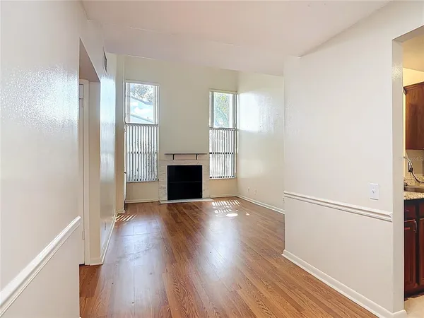an empty room with wooden floor fireplace and windows