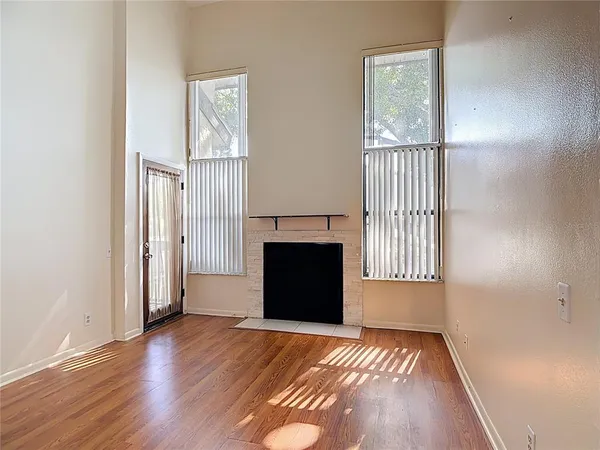 an empty room with windows and fireplace
