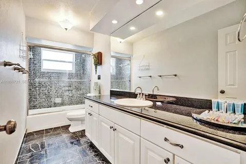 a spacious bathroom with a granite countertop sink a toilet a mirror and a shower