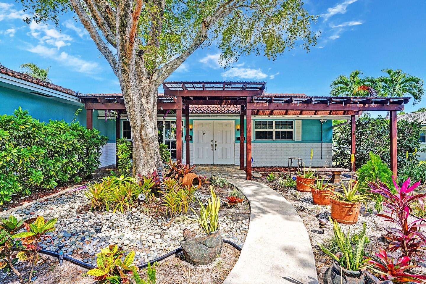 1245 Wiley Street Hollywood, FL 33019 - Photo 5 of 43 a front view of a house with a yard and a garden