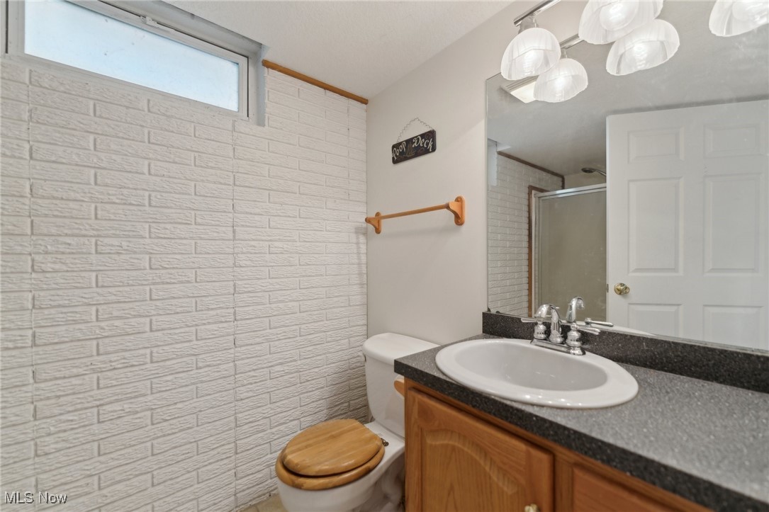 45230 Cemetery Road Wellington, OH 44090 - Photo 29 of 50 Bathroom with a stall shower, toilet, vanity, and brick wall