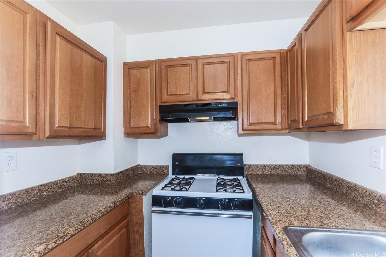 87-122 Helelua Street, Unit C204 Waianae, HI 96792 - Photo 5 of 19 a kitchen with granite countertop a sink stove and cabinets