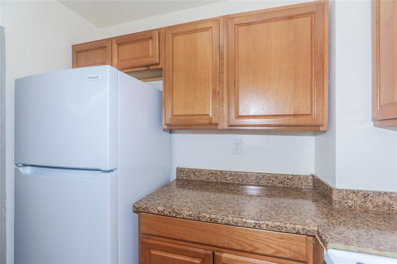 87-122 Helelua Street, Unit C204 Waianae, HI 96792 - Photo 6 of 19 a kitchen with granite countertop cabinets and a refrigerator