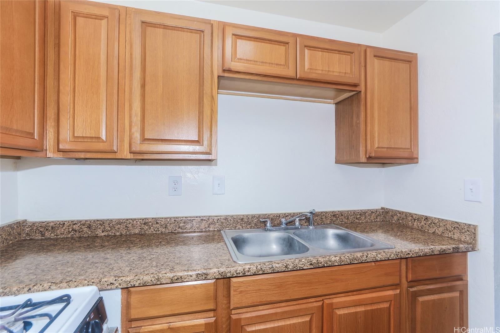 87-122 Helelua Street, Unit C204 Waianae, HI 96792 - Photo 7 of 19 a kitchen with granite countertop white cabinets and a sink